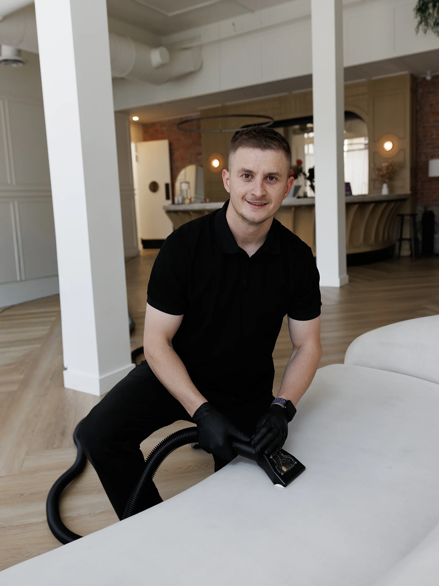 Andrew, owner of C&M Cleaning Services, deep-cleaning a sofa